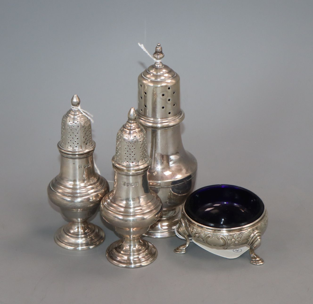 A pair of George V silver baluster-shaped peppers, London 1916, a silver sugar caster and a George