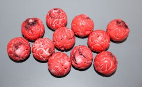 Eleven Chinese carved coral beads, diameter 1.8cm