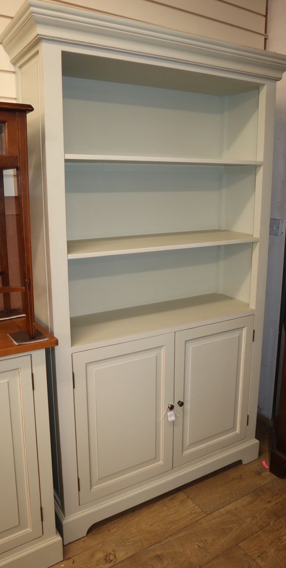 A modern painted open bookcase cupboard W.115cm