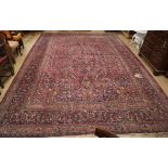 A Tabriz carpet with foliate pattern on a wine field (worn) approx. 480 x 340cm (holed)