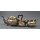 A late Victorian three-piece silver teaset, of oval half-fluted form with gadrooned edges, by HH,