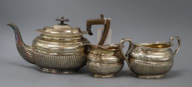 A late Victorian three-piece silver teaset, of oval half-fluted form with gadrooned edges, by HH,