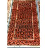 A Belouch red ground rug 204 x 115cm