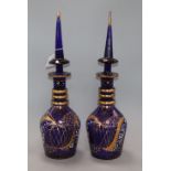 A pair of blue glass decanters with steeple shaped stoppers height 49cm