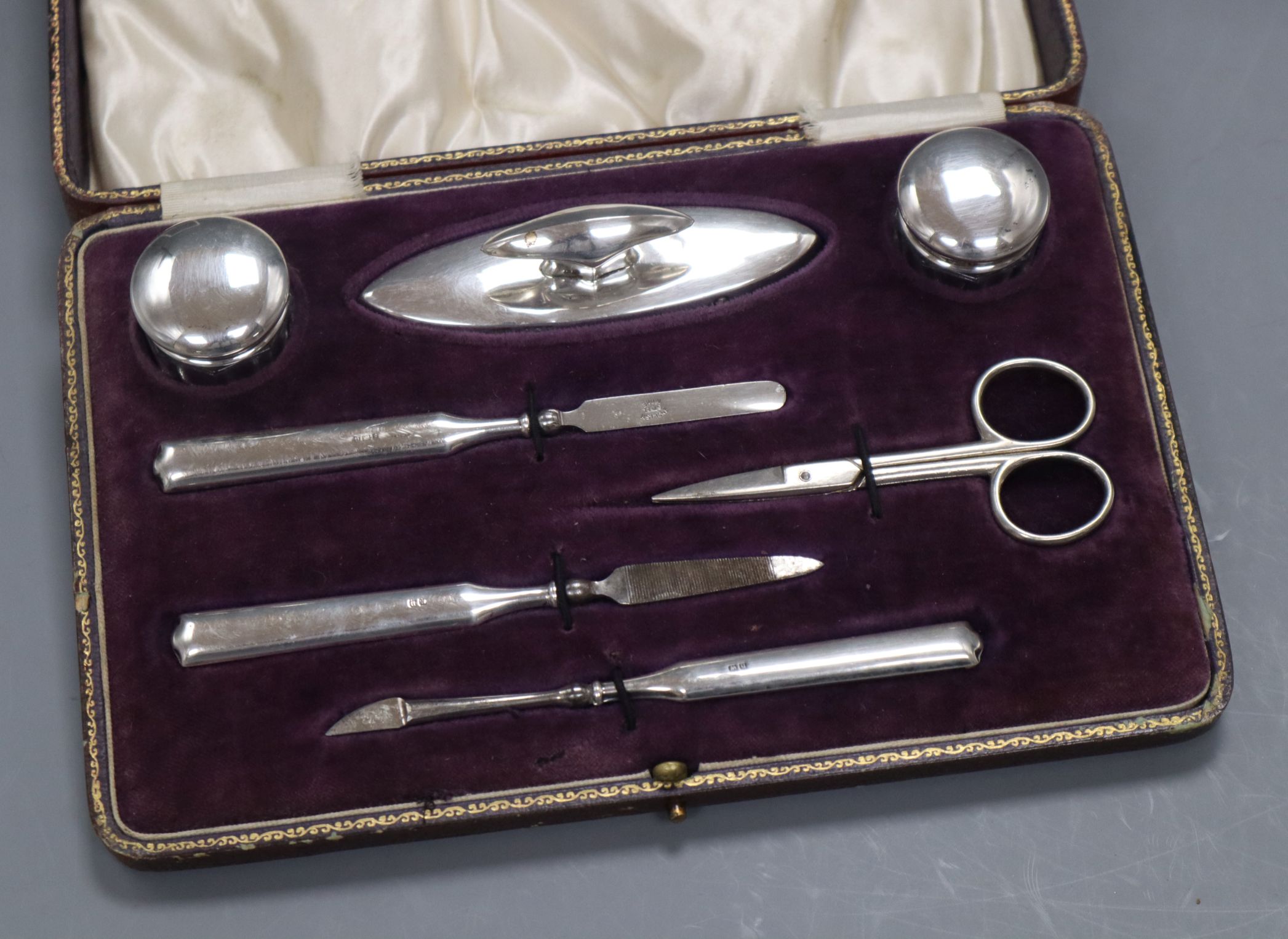 A cased George V silver mounted six piece manicure set with steel scissors.