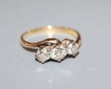 A yellow metal and 'plat', three stone diamond crossover ring, size N.