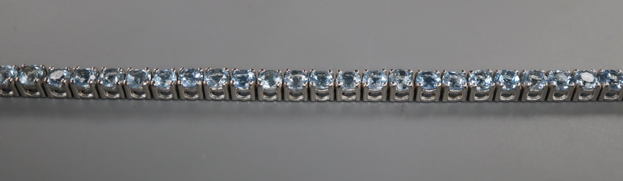 A 750 white metal and aquamarine set line bracelet, 18.2cm.