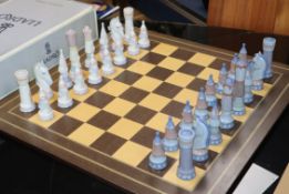 A Lladro chess set, 32 pieces, in medieval style with wooden inlaid board