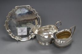 A late Victorian silver cream jug, a later silver sauceboat and silver waiter.