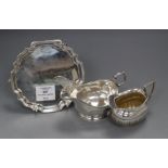 A late Victorian silver cream jug, a later silver sauceboat and silver waiter.