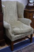 A Georgian style mahogany shaped wing armchair with green upholstery, square supports and H-