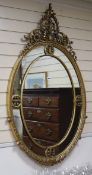 A George III style giltwood and gesso oval wall mirror, the leaf-wrapped frame having gilt