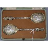 A cased pair of Edwardian ornate parcel gilt silver serving spoons, Robert Stebbings, London 1902,