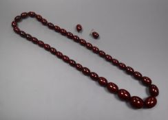 A single strand graduated simulated cherry amer bead necklace and two loose beads, gross weight