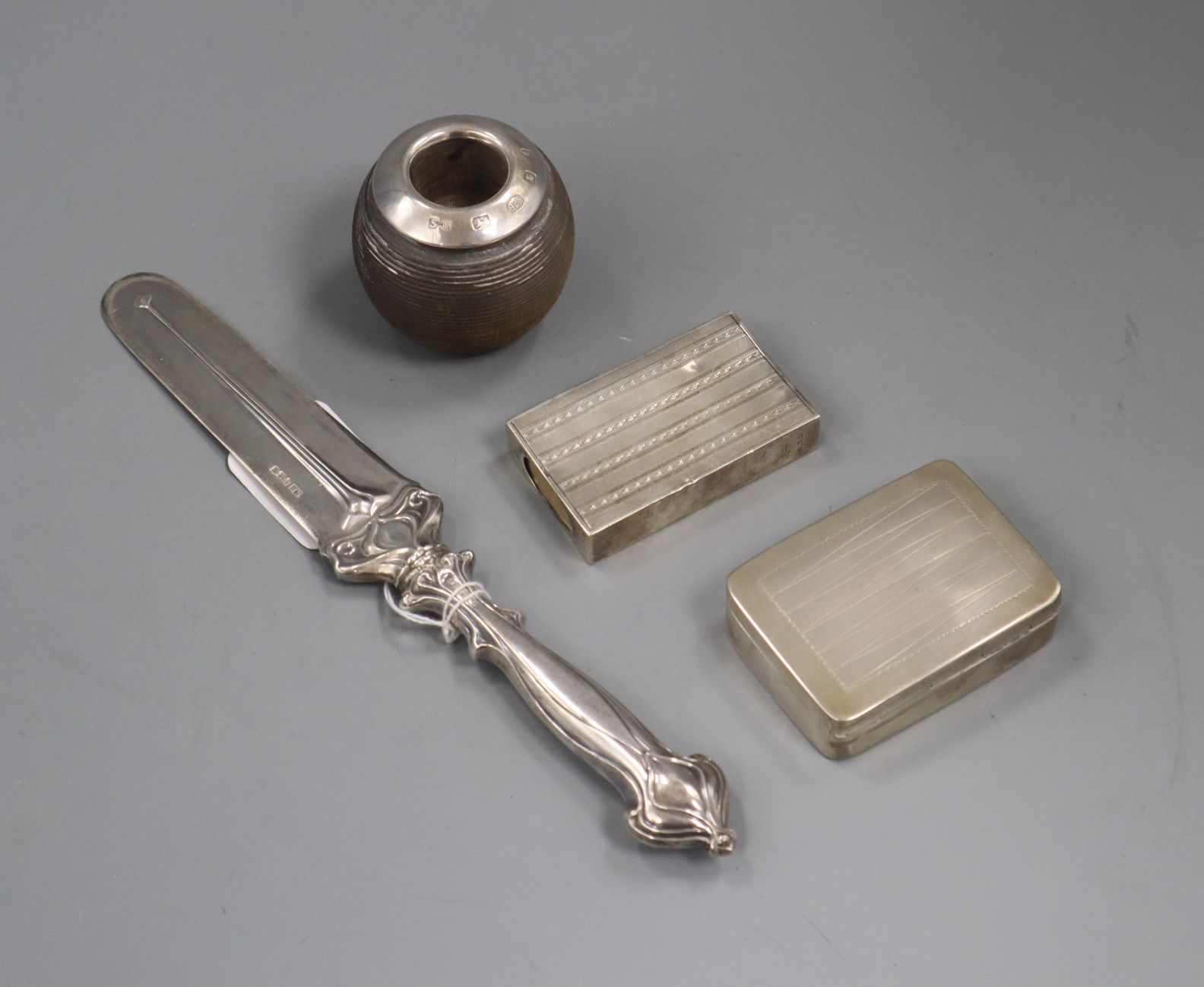 A silver mounted match strike, a silver letter knife, a white metal snuff box and a silver match box