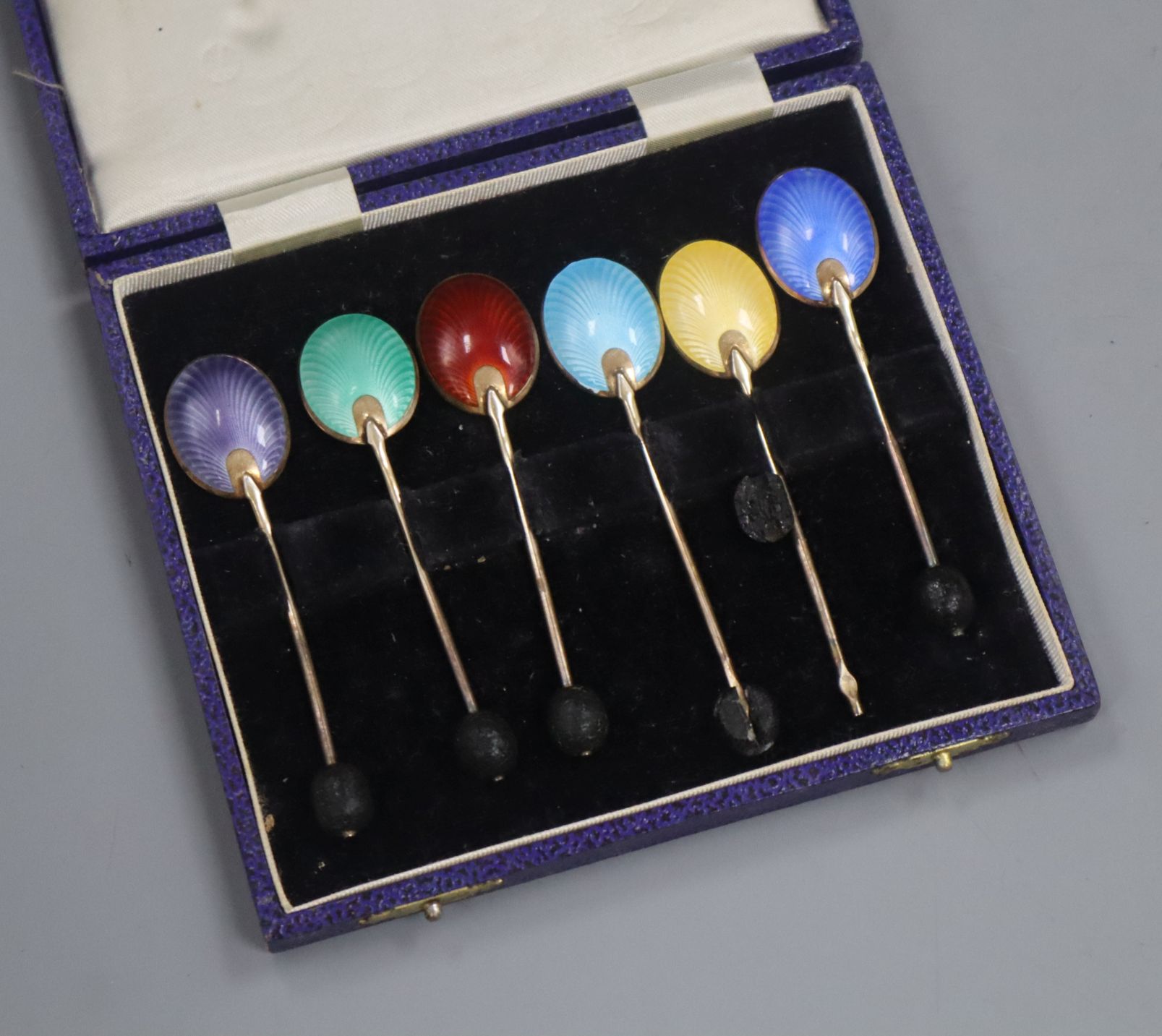 A cased set of six silver gilt and polychrome enamel bean end coffee spoons, Turner & Simpson,