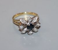 A modern yellow metal, sapphire and diamond cluster ring, size L.
