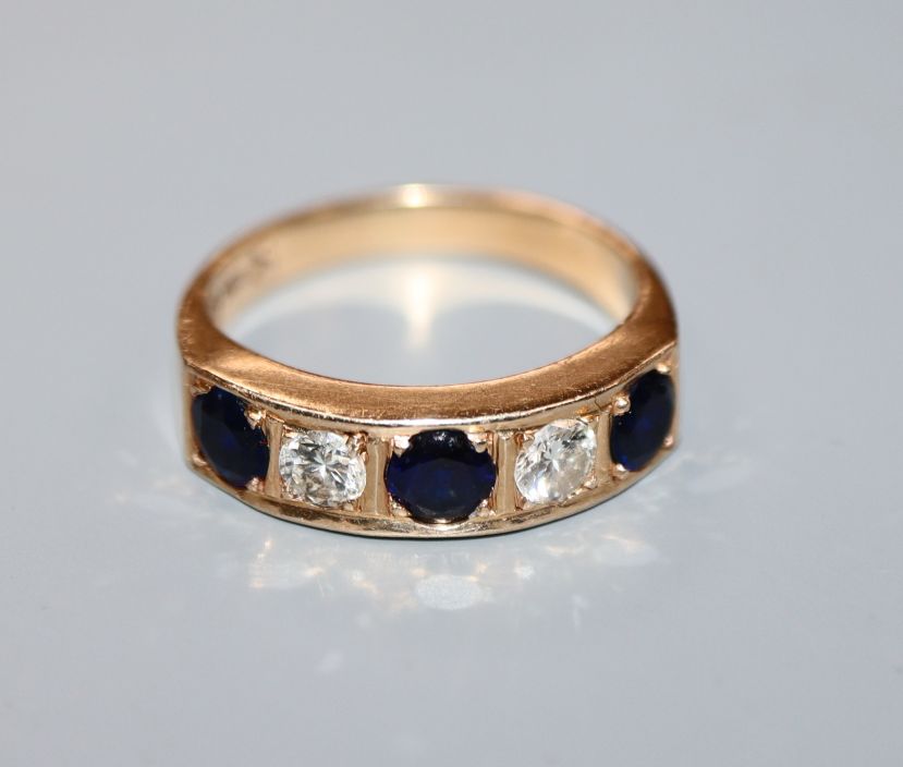 A 585 yellow metal, five stone sapphire and diamond set half hoop ring, size M.