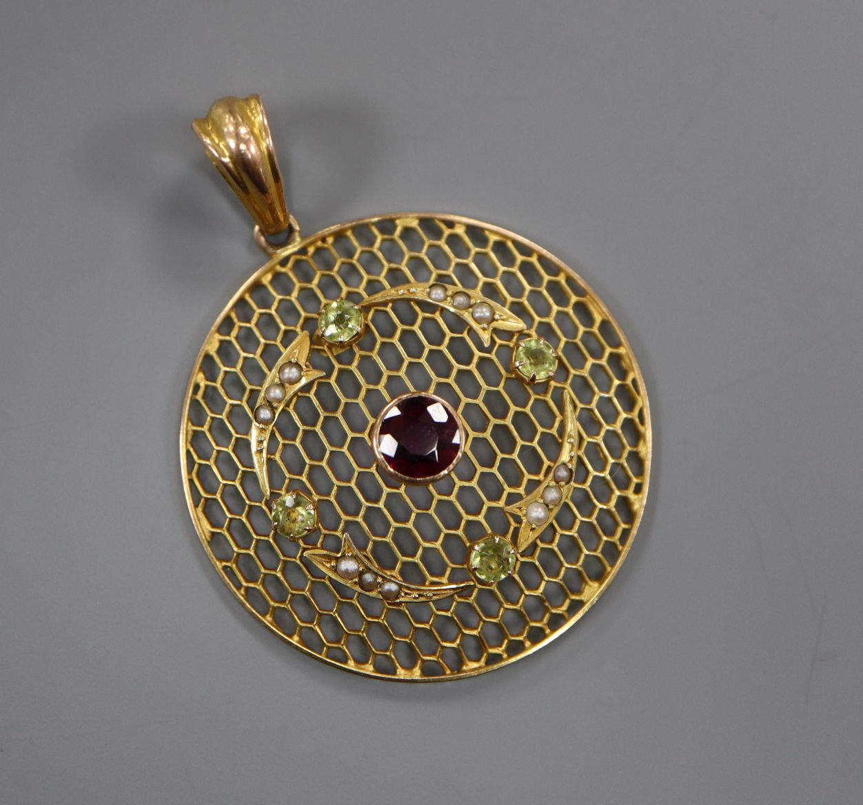A late Victorian 9ct circular pierced pendant, set with split pearls, peridot and a central