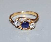 A modern 18ct gold three stone diamond and sapphire crossover ring, size K.