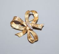 A diamond and 18ct yellow and white gold 'tied-ribbon' brooch, by John Donald, 28mm.