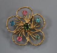 An openwork flower brooch centred by a green tourmaline with five gem-set stamens, 9ct gold textured