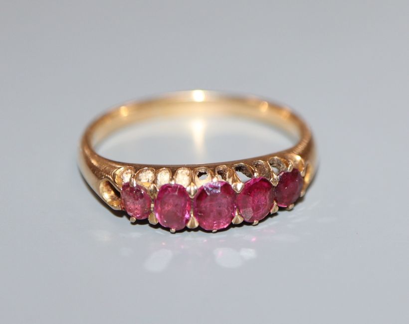 A yellow metal and graduated five stone ruby half hoop ring, size O.