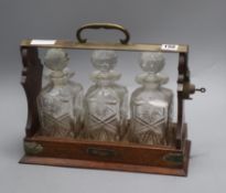 A late Victorian plated mounted oak three decanter tantalus