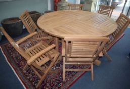A circular teak garden table and six chairs (four plus two carvers) Table diameter 150cm