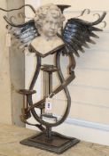 A wrought iron three branch candelabra with lyre shaped base, surmounted with reconstituted stone