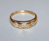 An 18ct. gold three stone gypsy set diamond ring, size N/O.