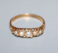 An early 20th century 18ct yellow metal and graduated split pearl set half hoop ring, size M.