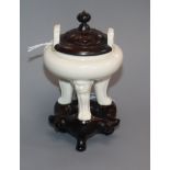 A Chinese small blanc de chine tripod censer, 17th century, wood cover and stand, repaired handle