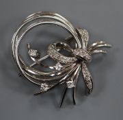 A modern 585 white metal and diamond set scroll bow brooch, 35mm.