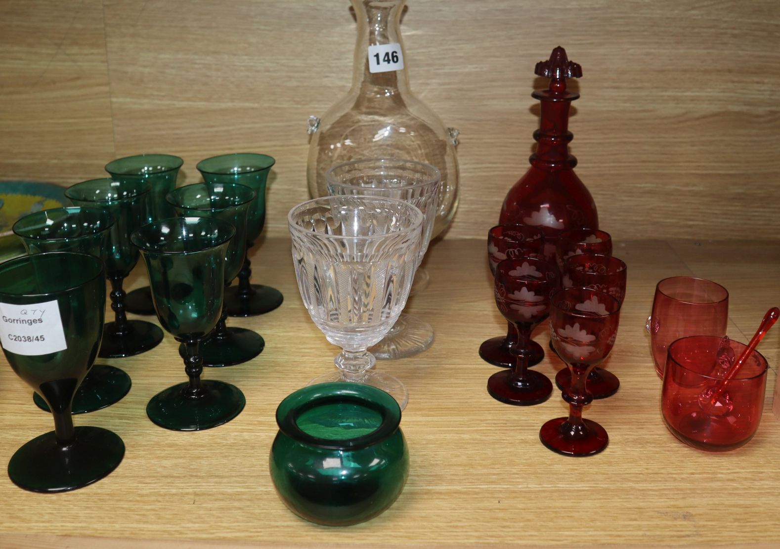 A set of six dark green wine glasses, a vine etched ruby glass decanter and five matching liqueur