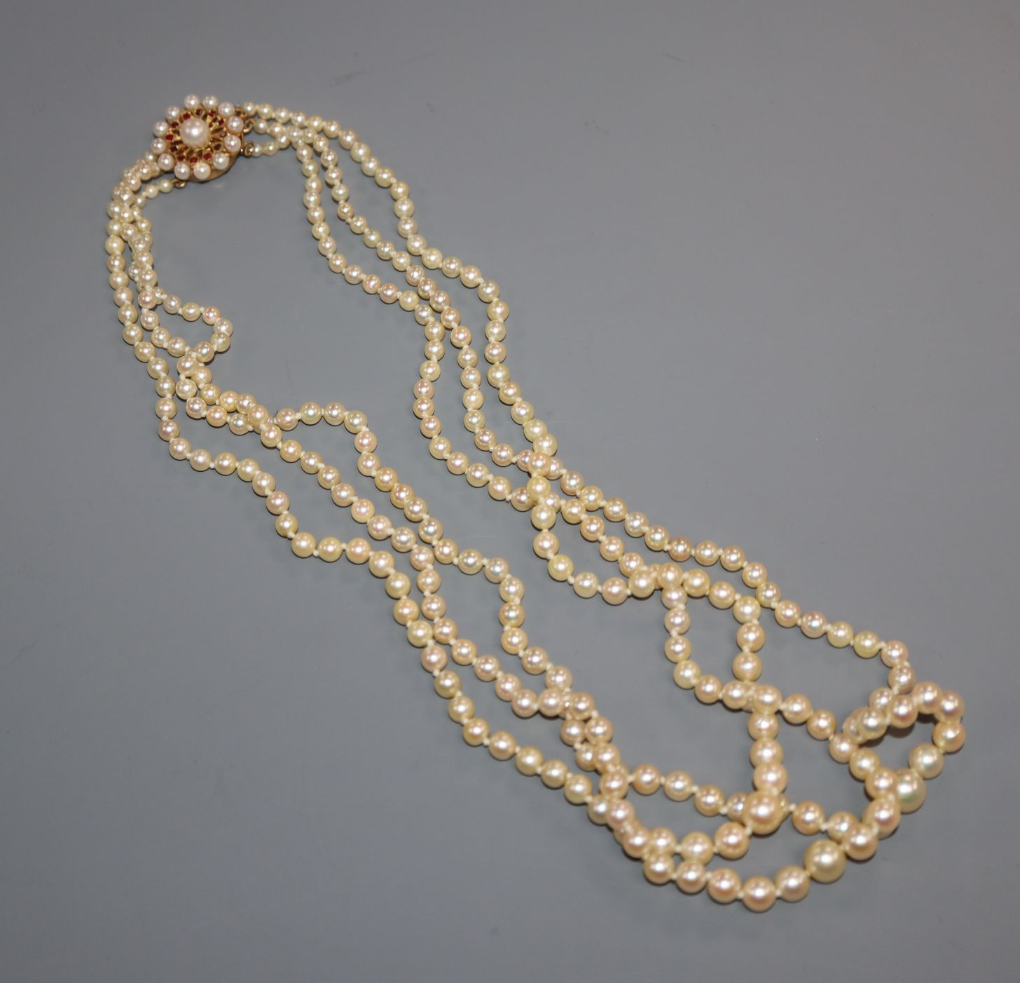 A triple strand graduated cultured pearl necklace with 9ct, cultured pearl and garnet set clasp,