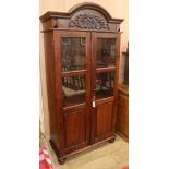 A carved hardwood cabinet with domed topped enclosed by glazed doors, W.96cm