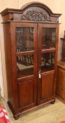 A carved hardwood cabinet with domed topped enclosed by glazed doors, W.96cm