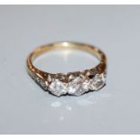 An 18ct and plat, three stone diamond ring, with diamond set shoulders, size M.