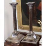 A pair of corinthian column plated candlesticks, with square bases