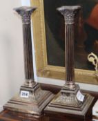 A pair of corinthian column plated candlesticks, with square bases
