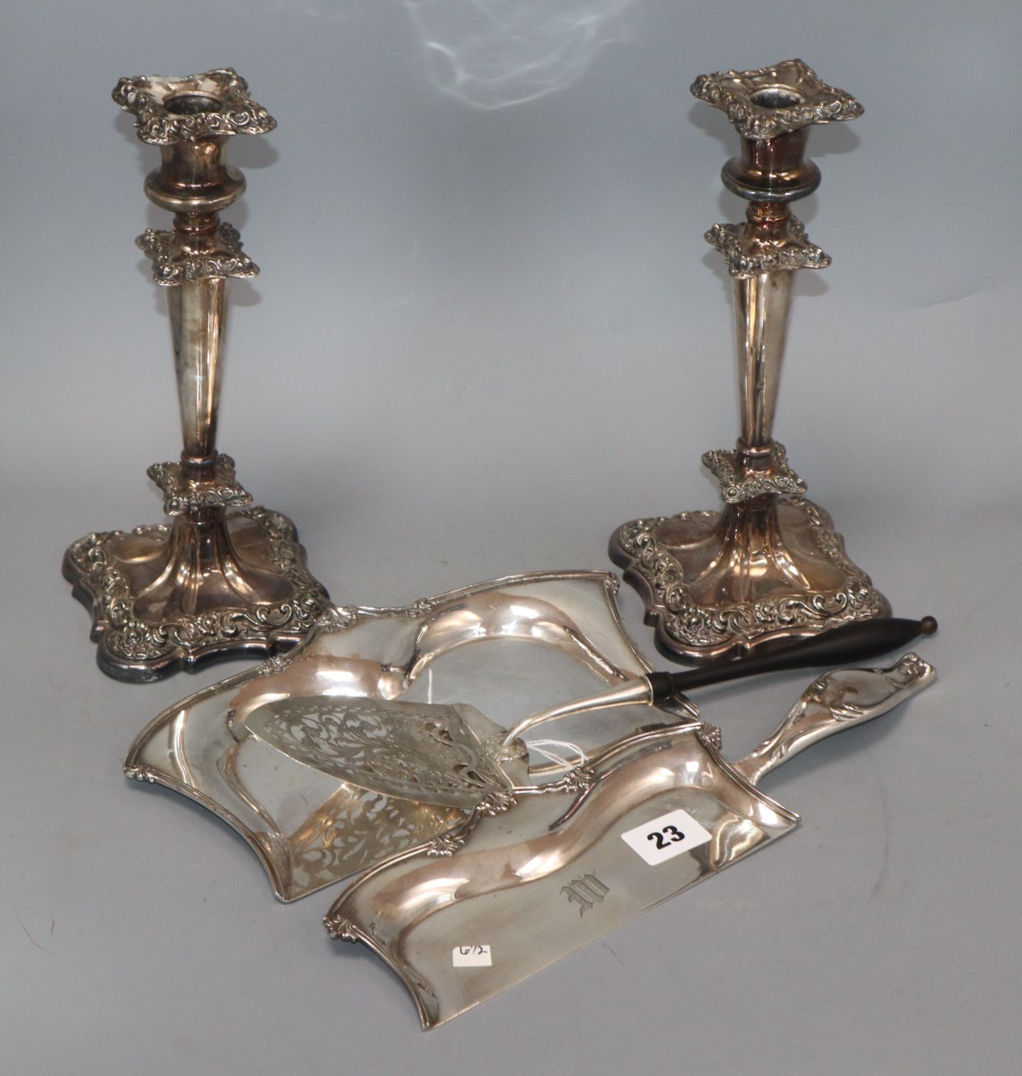 A pair of plated candlesticks, a crumb scoop and a presentation trowel