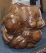 A carved hardwood figure modelled as a man in curled seated position