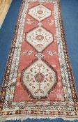 A Caucasian red ground runner 290 x 100cm