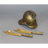 An early 20th century model brass fireman's helmet money box, two trench art paperknives and a shell