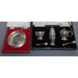 A three-piece silver condiment set and a silver Churchill commemorative dish (both cased)