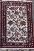 A Persian cream ground rug with central field of foliate motifs