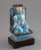 A Chinese turquoise and manganese glazed biscuit figure of Zhenwu, 17th century, seated on a