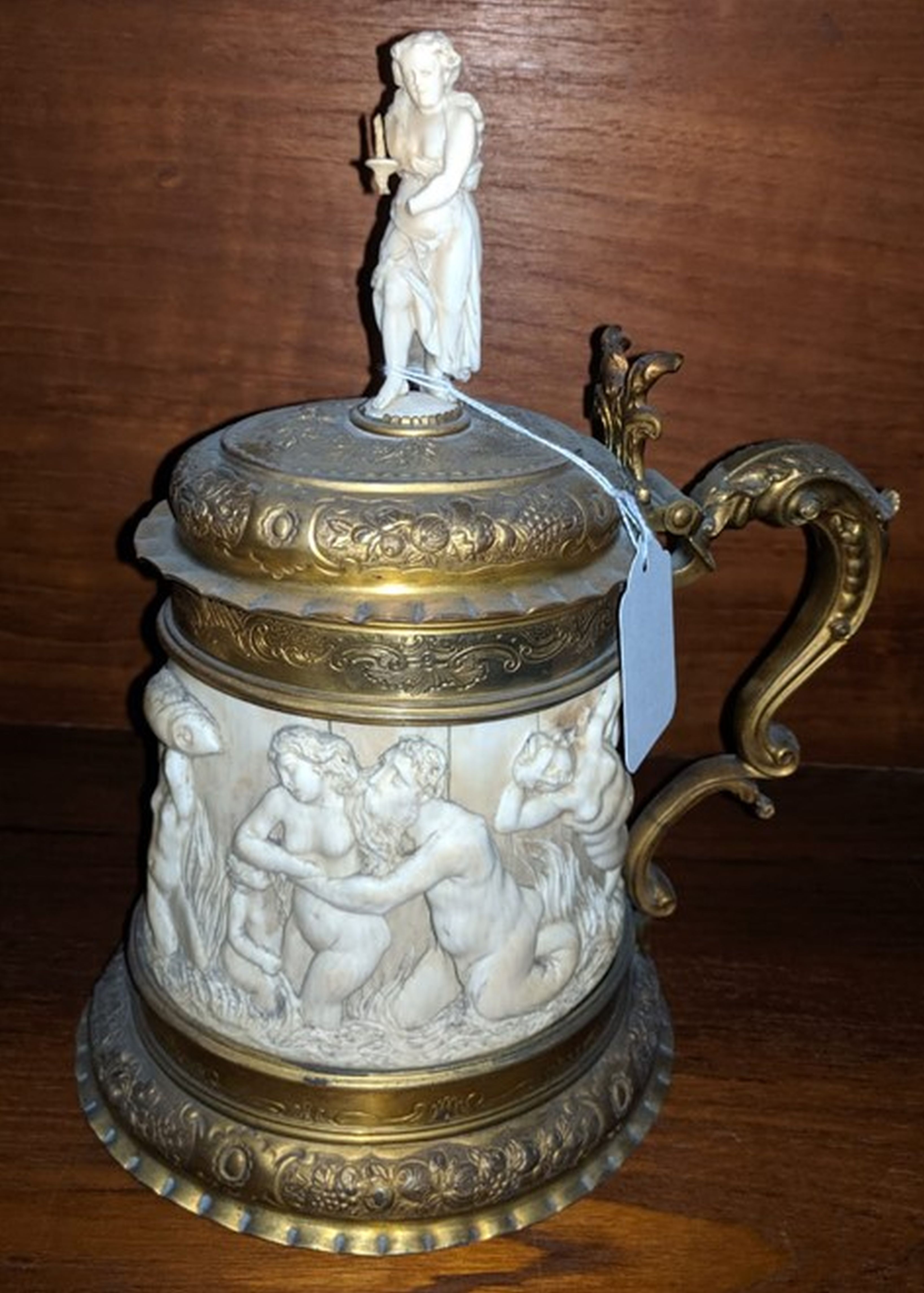 A 19th century German ormolu mounted ivory tankard, carved in relief with a frieze of tritons and