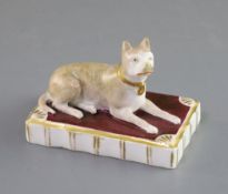 A Rockingham porcelain figure of a recumbent terrier, c.1830, the maroon base with fluted edge,